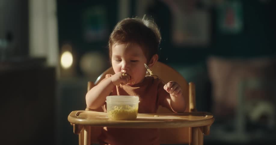 Toddler doing a mess while eating on a high chair