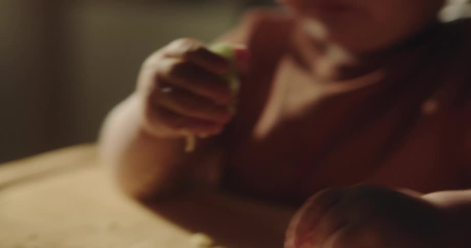 Portrait of a baby sitting and eating a vegetable