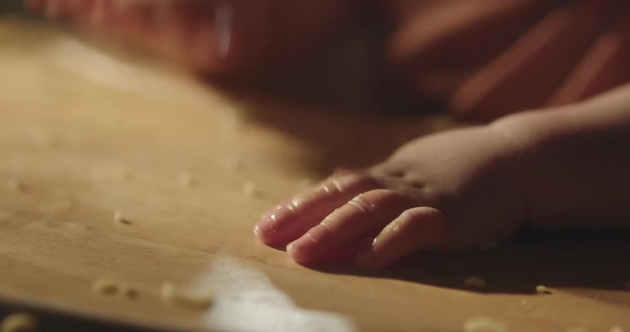 The hands of a little baby on a chair hitting the table