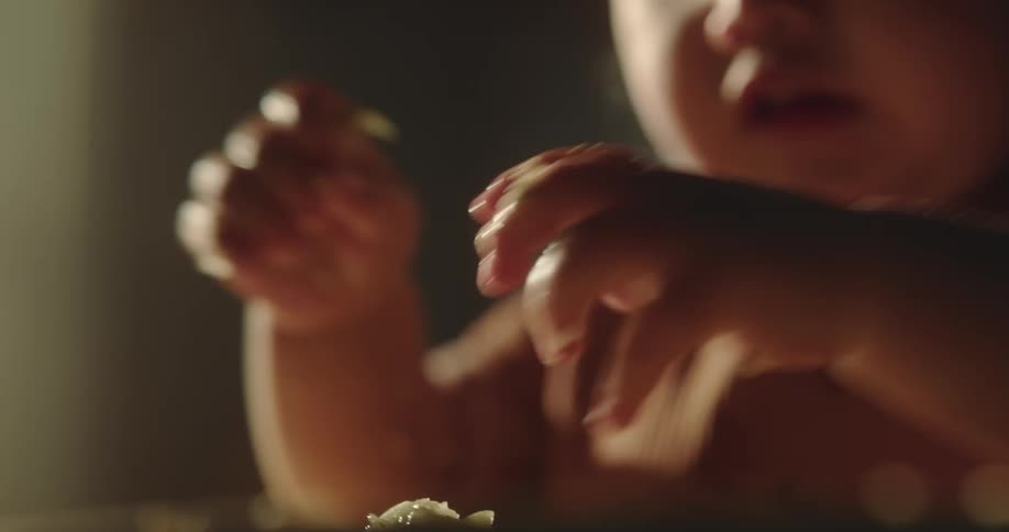 Closeup of a small child running their hands through food