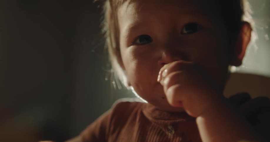 A baby eating food and making a face