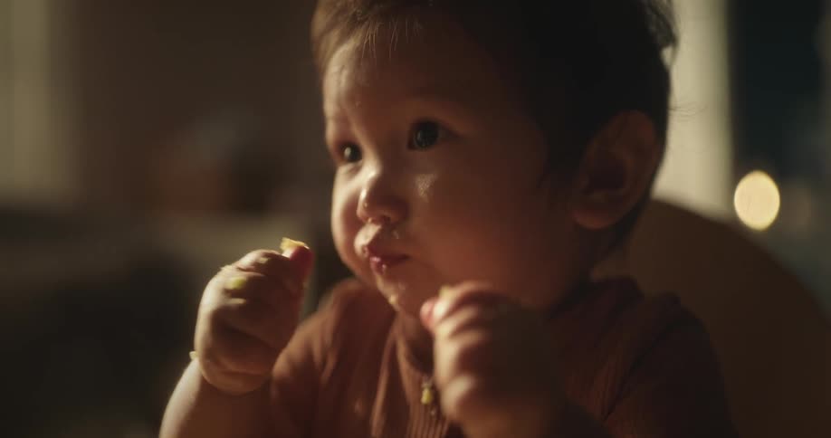 A baby sitting in a high chair eating