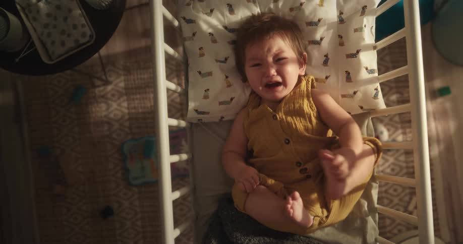 Baby girl lying in the crib and crying