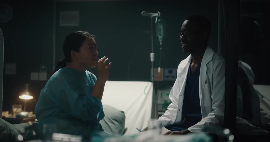 A woman sitting on a hospital bed talking to a doctor