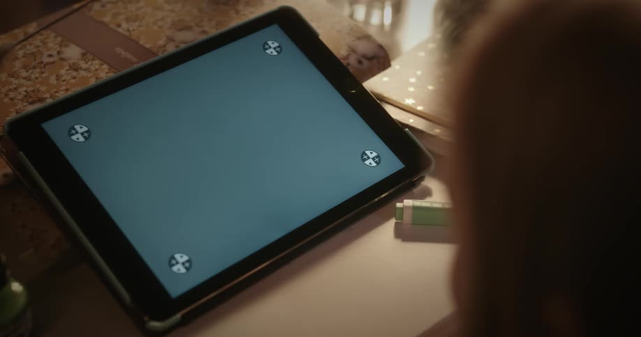 A persons head is moving near a tablet with a replacement screen on a table