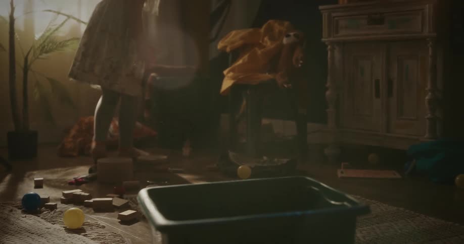 Girl puts toys away in bin set on floor