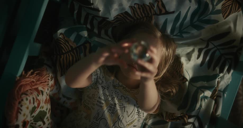 Girl lying on the bed looking at a small crystal ball