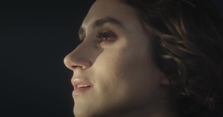 Light shines on a womans face as her hair moves in the breeze during a near death experience