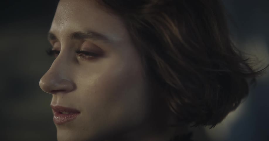 A womans face whose expressions change to happy when natural light hits her skin