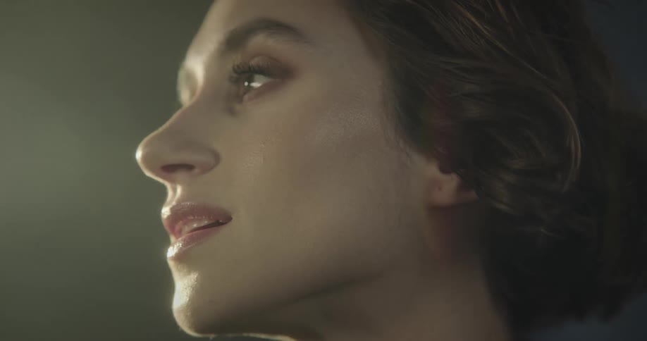 Woman smiles on windy night as light and shadow play across her face