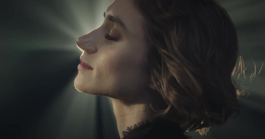Woman leans her head back on windy night as spotlight shines across her