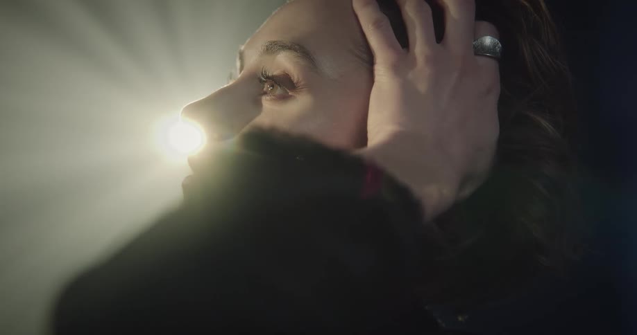 Portrait of a woman putting her hands in her hair looking happy with reflections of lights