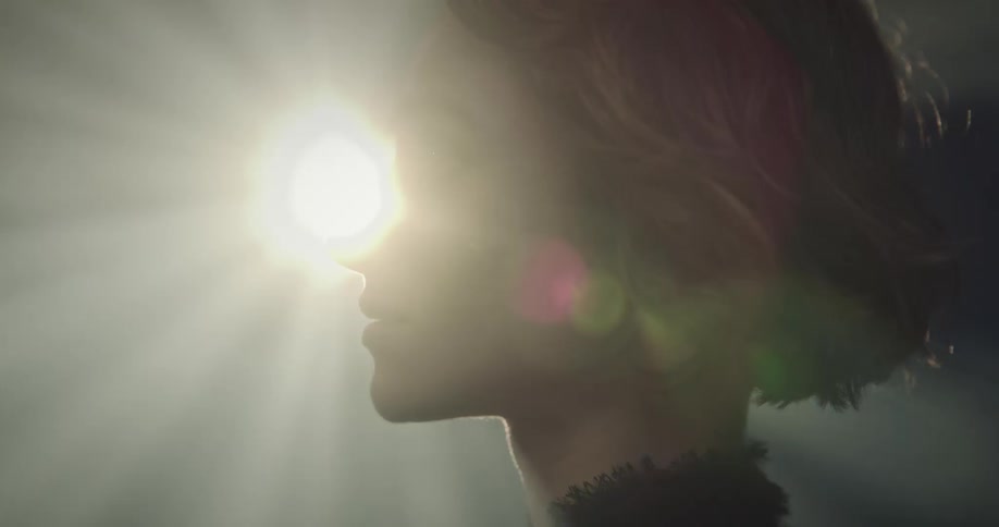 Side portrait of a young woman in a dark room with reflections of light under her face
