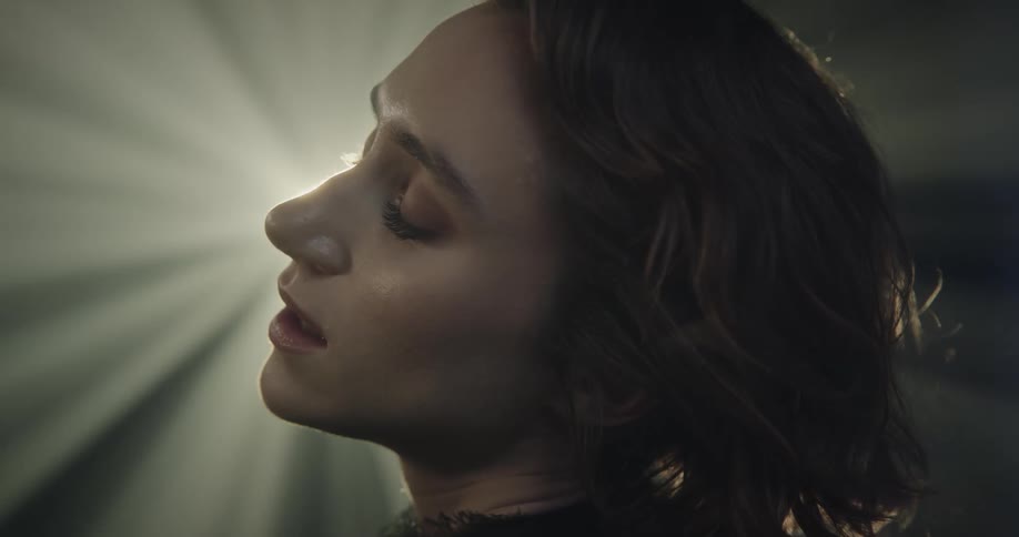 Woman with short hair wearing an expression of lightness and happiness with lights reflecting on her face