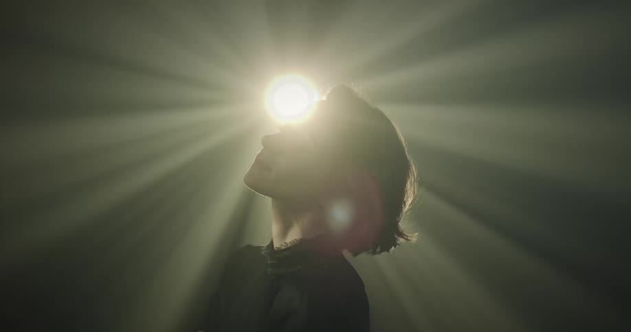 Light shines on a womans face as her hair moves during a near death experience