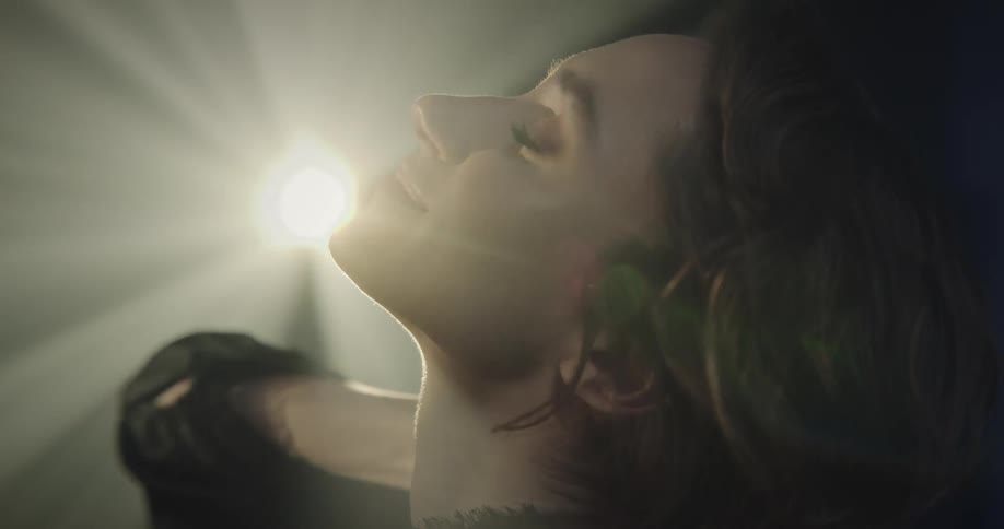 Portrait of a young woman with a facial expression and light reflecting on her face