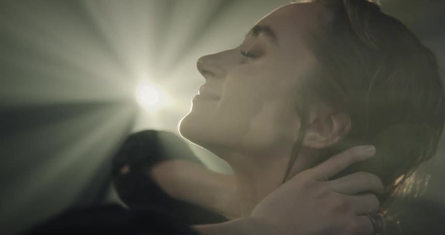 Woman running her hands through her hair with a facial expression of happiness and a reflection of light on her face