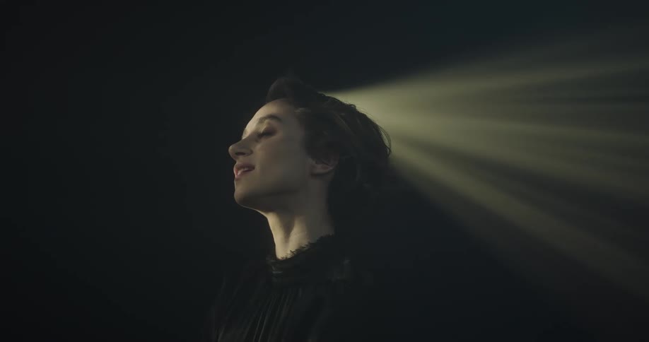 A woman is smiling as a light passes over her head