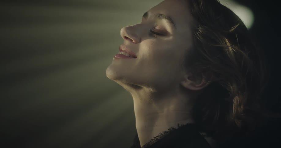 Closeup of a womans face illuminated by a beam of light