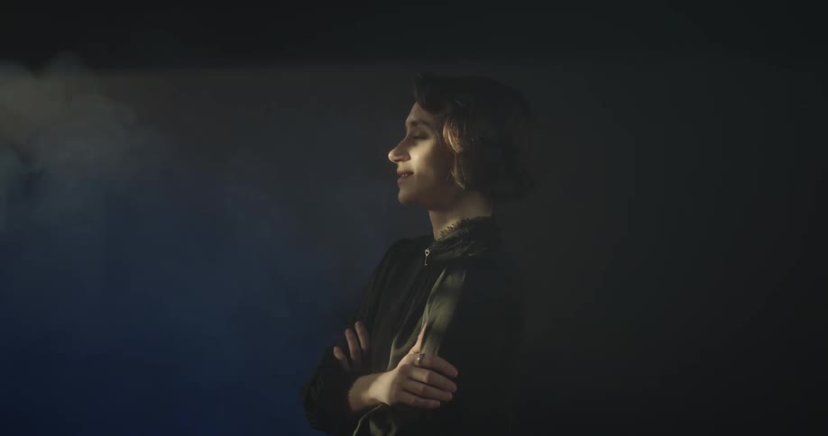 Woman with crossed arms and a happy facial expression when smoke comes to her face