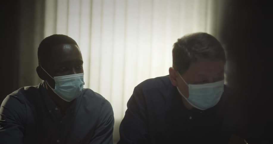Dois homens colocando as mos em uma pessoa deitada em um quarto de hospital