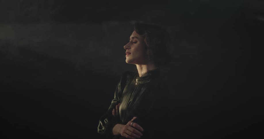 Woman stands in a room filled with smoke under moving lights