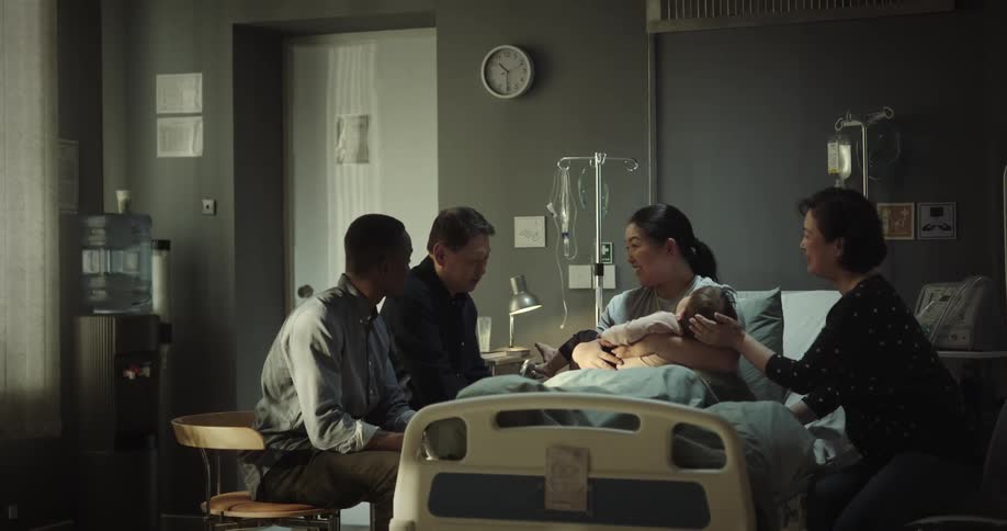 Family in the hospital sitting around a patient who is holding a baby