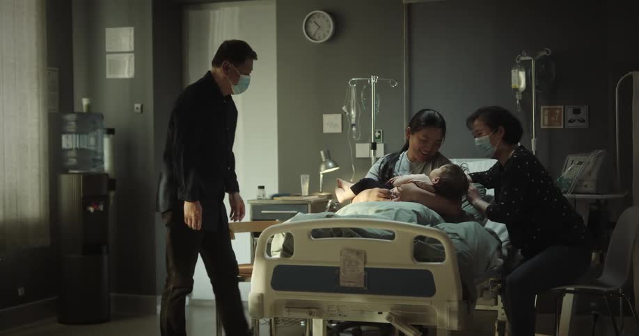 Parents bringing their granddaughter to their daughter who is in a hospital bed and becoming extremely happy