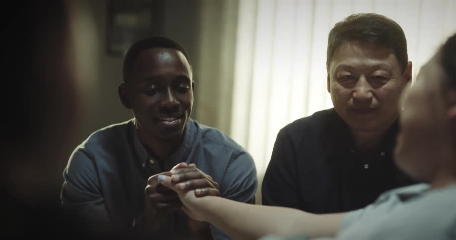 Man holding hands with a woman in a room with other people all smiling