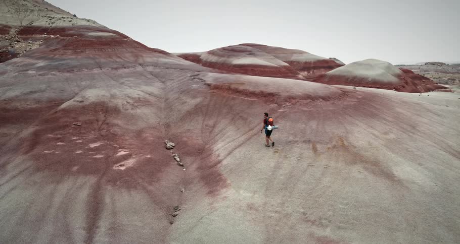 Man walking on dirt mounds in a natural environment during the day