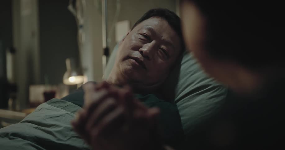 Woman caressing the face and hands of a man lying in a hospital bed