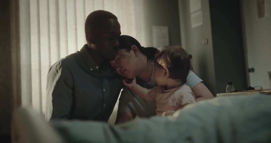 Family sitting next to a hospital bed hugging each other