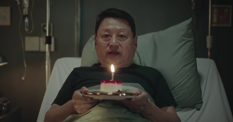 Patient lying in bed holding a cake with a smiling candle