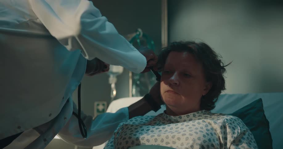 Doctor checking the ear of a patient lying in a hospital bed