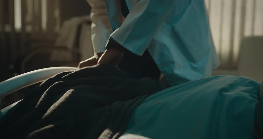 Doctor in a hospital room reading a paper and then examining the feet of a patient