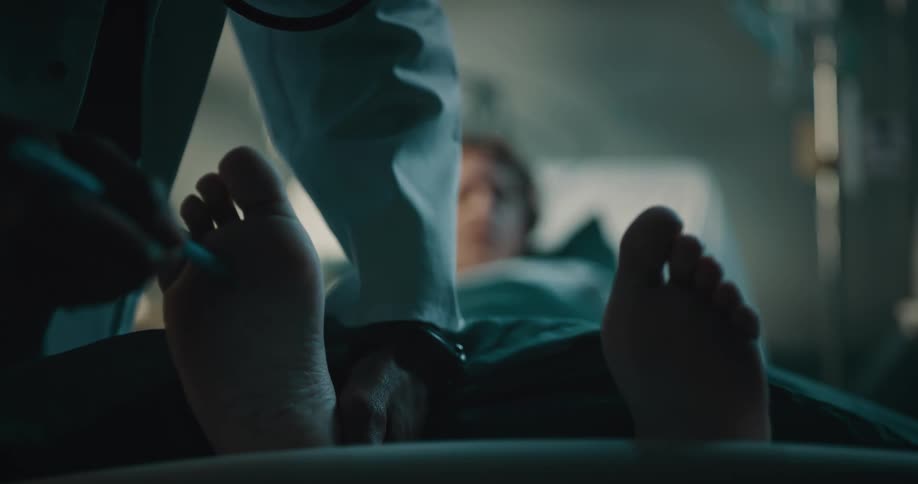 View of a female patient lying down with a doctor examining her foot and having a conversation with the patient