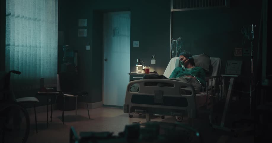 Female patient with an oxygen mask lies in hospital bed