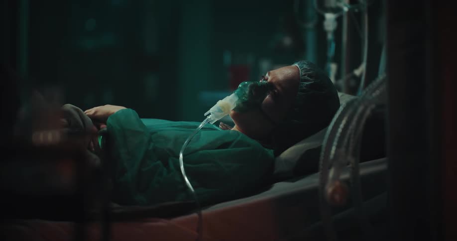 Female patient lying in the hospital bed adjusting her oxygen mask