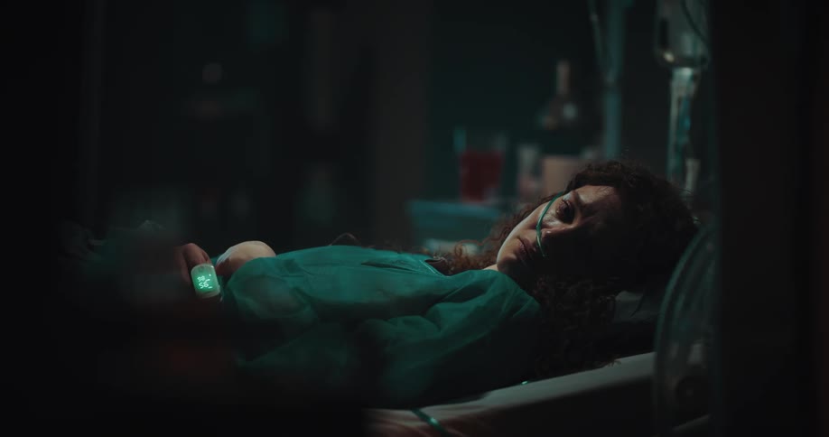 Woman lying on a hospital bed with medical equipment wearing a sad and weak facial expression