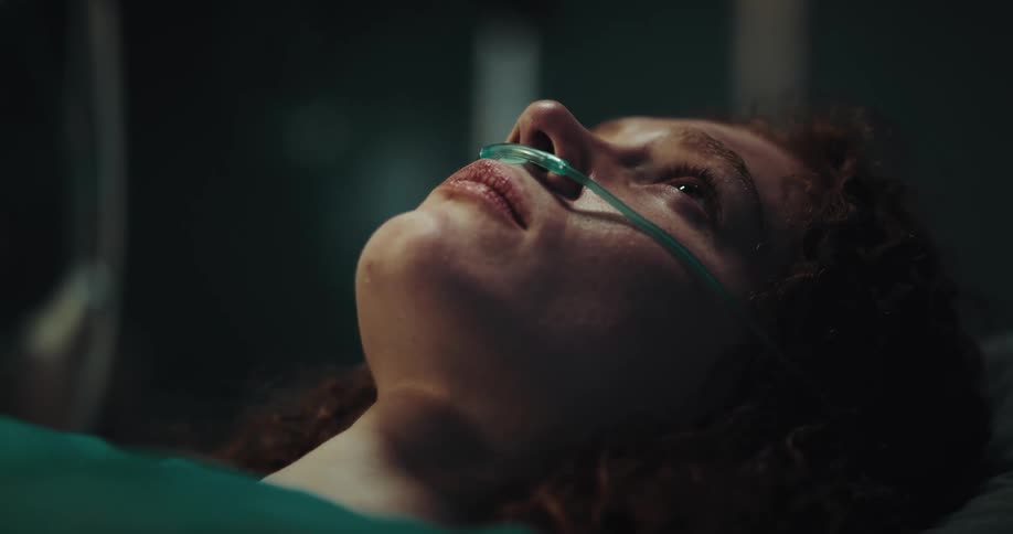 Female patient lying down with a nasal cannula with a sad facial expression