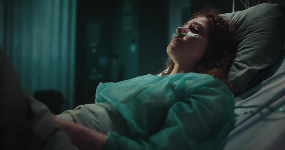 A woman lies in a hospital bed and cries