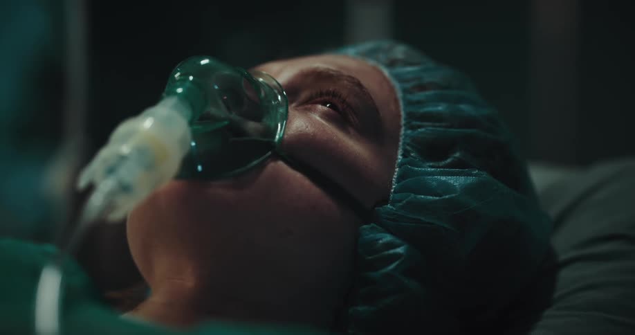 Portrait of a woman with an oxygen mask lying in a hospital bed