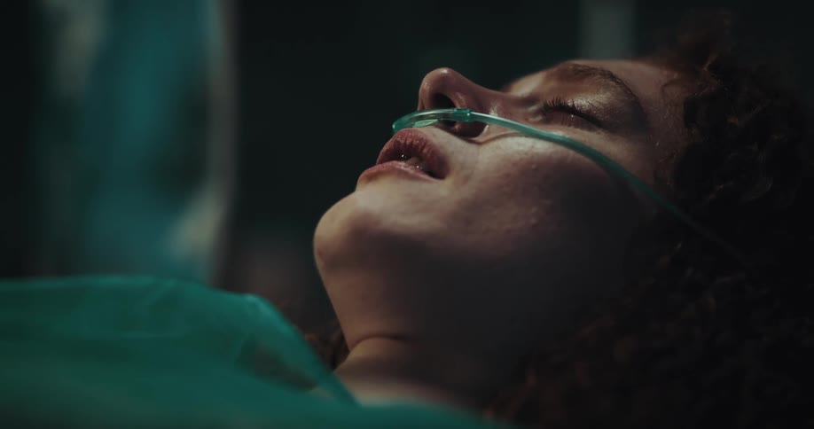 A woman is laying in a hospital room crying and talking on the phone