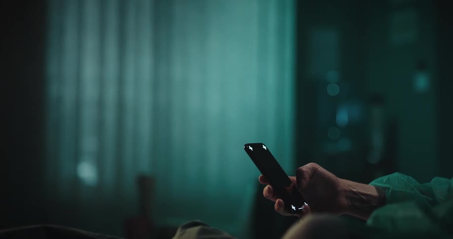 A man holding a cellphone moves his thumb across the black screen