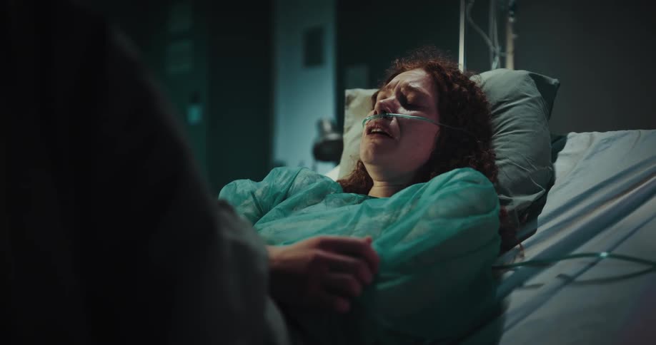 Woman in a hospital bed with medical equipment crying
