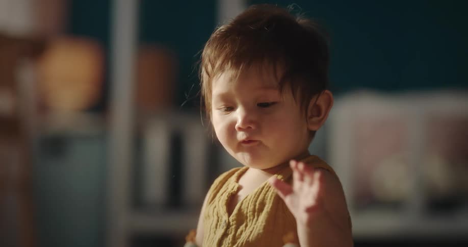 A baby sitting on the floor clapping his hands