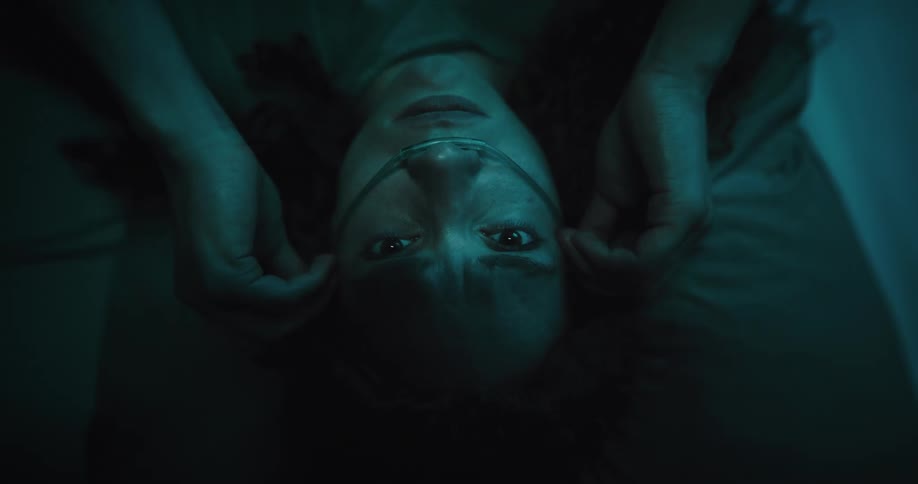 Woman lying in a hospital bed with a nasal cannula and a scared expression