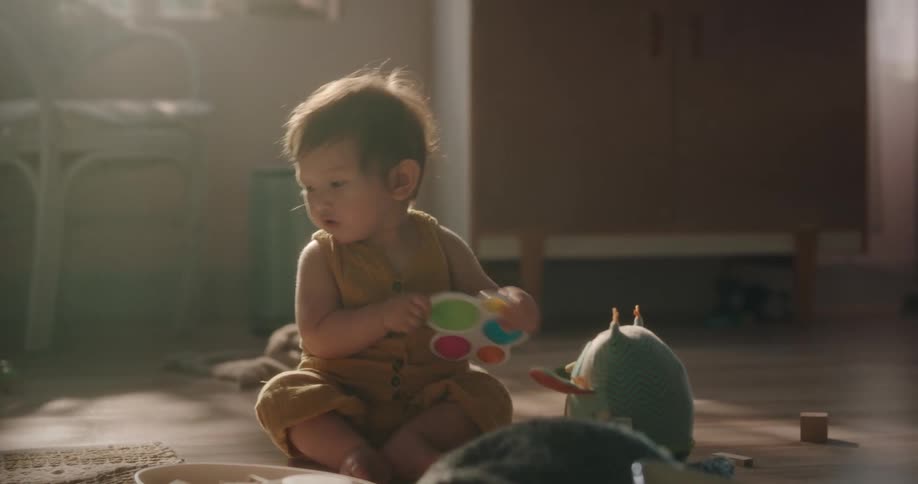 Toddler sits on floor playing with toys