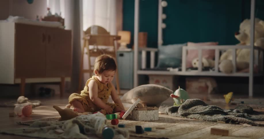 Baby sitting on a rug in a room surrounded by toys