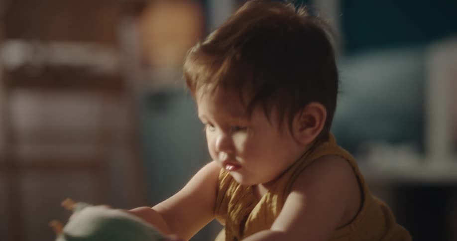 A baby is sitting on the floor and playing with a ball